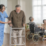 young asian female nurse care giver helping asian senior old man with mobility walker living area nursing home senior daycare centernurse take care elderly patient with cheerful concentrate (1)